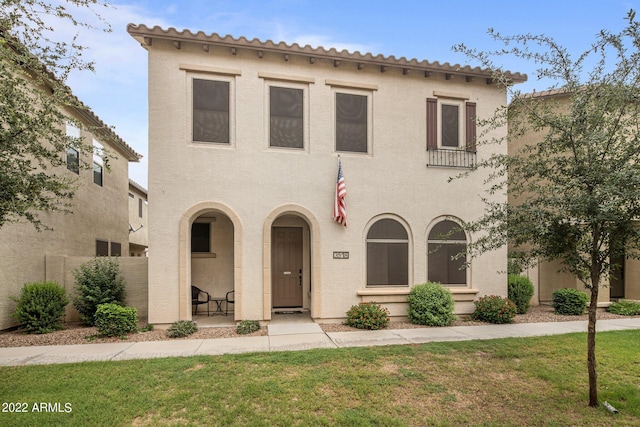 mediterranean / spanish house with covered porch, stucco siding, and a front lawn