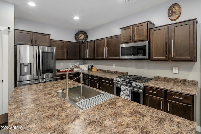 kitchen featuring recessed lighting, a sink, dark brown cabinetry, appliances with stainless steel finishes, and dark countertops