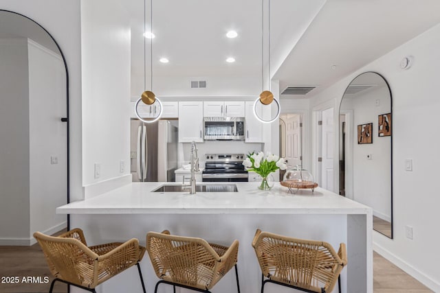 5401 E Van Buren St Unit 1088, Phoenix, AZ 85008 - kitchen with appliances with stainless steel finishes, light wood-style floors, a kitchen breakfast bar, recessed lighting, and white cabinets