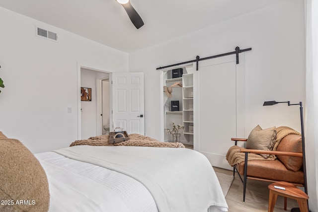 5401 E Van Buren St Unit 1088, Phoenix, AZ 85008 - bedroom with a barn door, light wood-style flooring, and ceiling fan