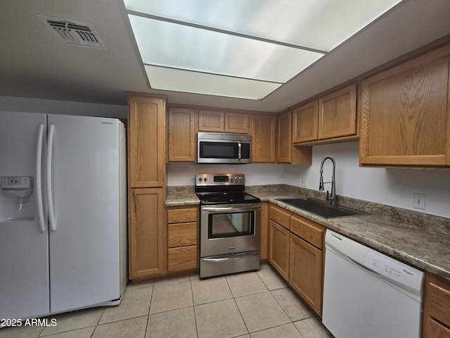 kitchen with appliances with stainless steel finishes, sink, and light tile patterned floors