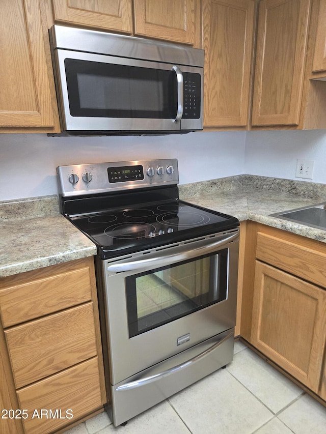 kitchen with appliances with stainless steel finishes, sink, and light tile patterned floors