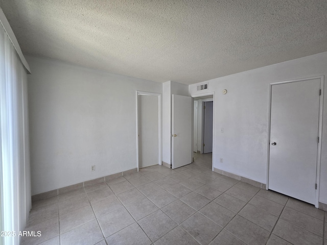 unfurnished bedroom with a textured ceiling and light tile patterned floors