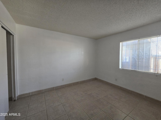 unfurnished room with light tile patterned floors and a textured ceiling