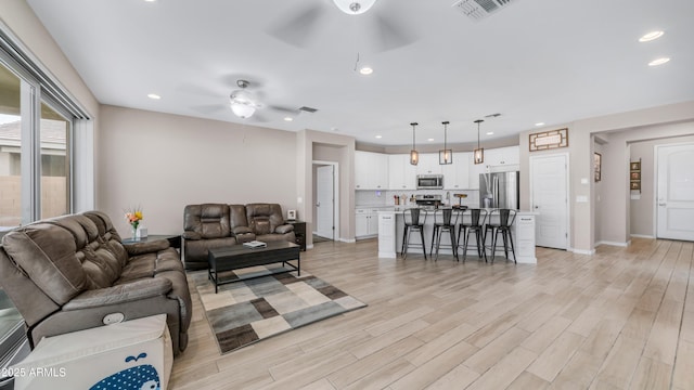 living area featuring ceiling fan, light wood finished floors, recessed lighting, and baseboards