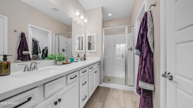 bathroom featuring a stall shower, double vanity, and a walk in closet