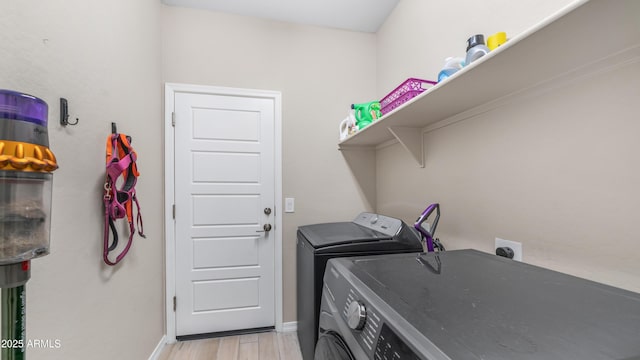 laundry area featuring washer and dryer, baseboards, and light wood-style floors