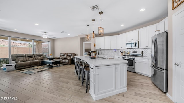 kitchen with stainless steel appliances, open floor plan, a kitchen breakfast bar, light countertops, and tasteful backsplash