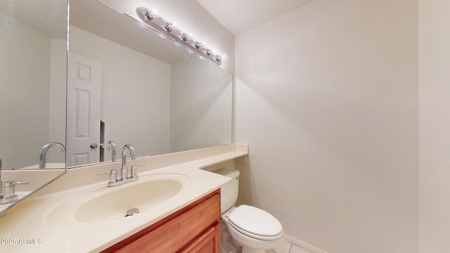 half bath featuring baseboards, vanity, and toilet