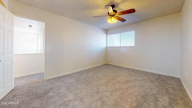 carpeted empty room with a textured ceiling, a ceiling fan, and baseboards