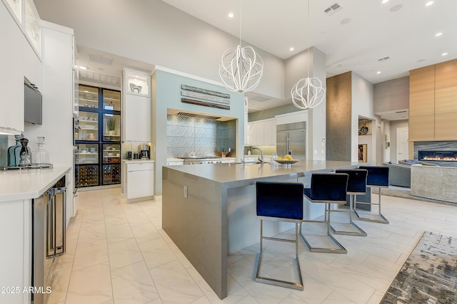 kitchen featuring backsplash, pendant lighting, a chandelier, white cabinetry, and built in fridge