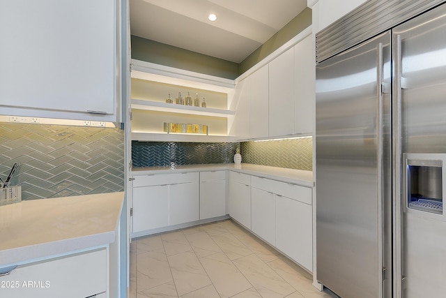 kitchen with white cabinets, backsplash, and built in fridge