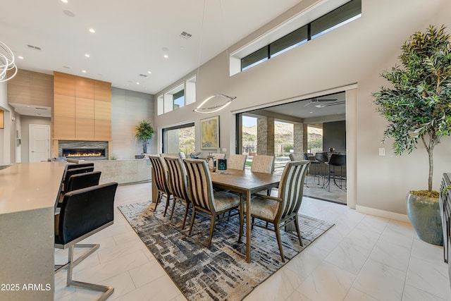 dining area with a fireplace, a towering ceiling, and plenty of natural light