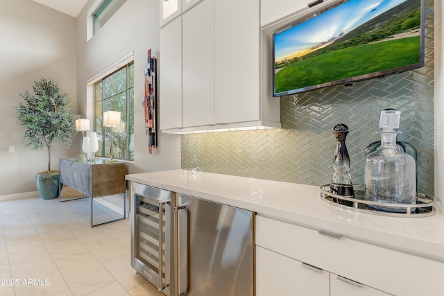 kitchen featuring refrigerator, white cabinetry, beverage cooler, and tasteful backsplash