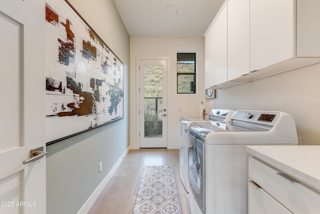 laundry area with washer and dryer, light tile patterned flooring, and cabinets