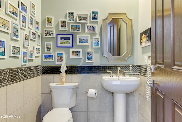 bathroom featuring toilet and tile walls