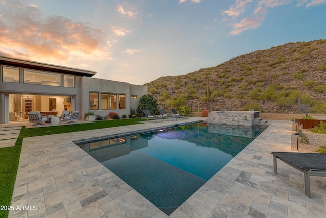 pool at dusk with a mountain view and a patio