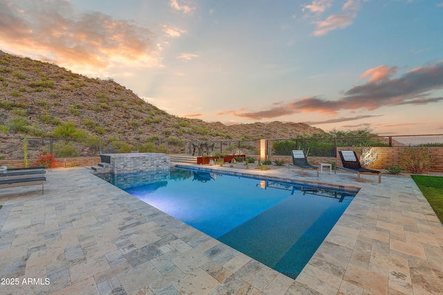 pool at dusk featuring a mountain view and a patio