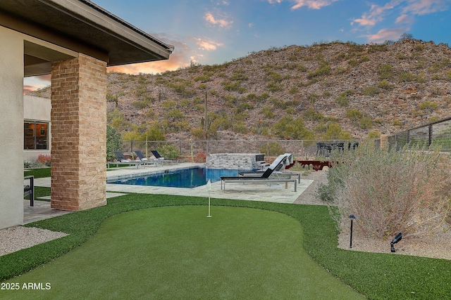 pool at dusk with a patio area