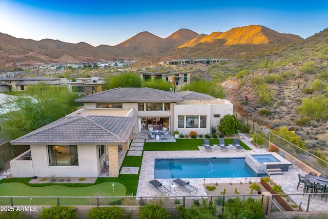 rear view of house with a mountain view, a swimming pool with hot tub, and a patio