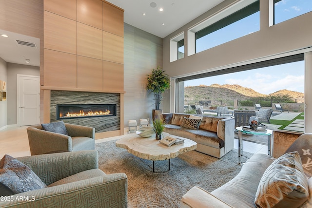 living room featuring a mountain view, a large fireplace, a towering ceiling, and light tile patterned floors