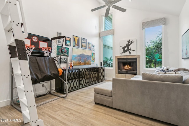 living room featuring ceiling fan, a fireplace, a healthy amount of sunlight, and light wood-type flooring