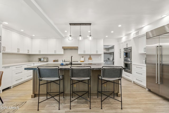 kitchen featuring white cabinetry, stainless steel appliances, and a center island with sink