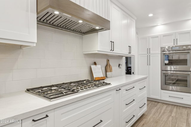 kitchen featuring appliances with stainless steel finishes, decorative backsplash, extractor fan, and white cabinets