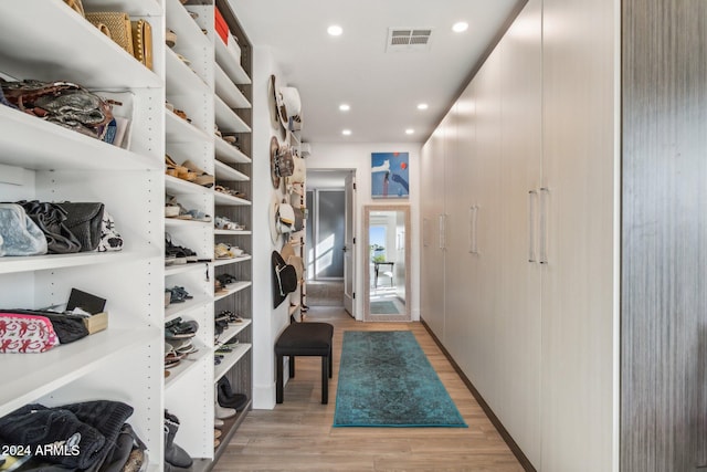 walk in closet with light hardwood / wood-style flooring