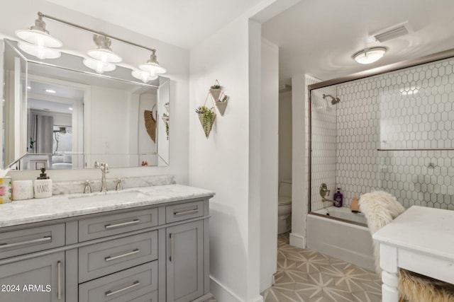 full bathroom featuring toilet, vanity, and shower / bath combination with glass door