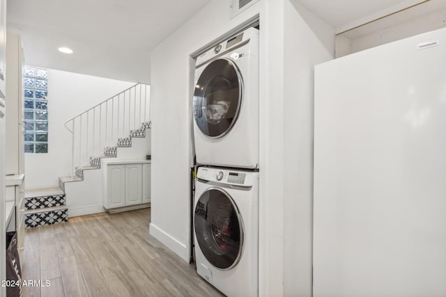 clothes washing area with stacked washer and clothes dryer and light hardwood / wood-style floors