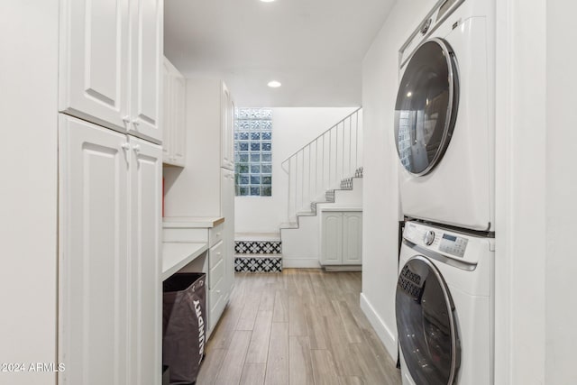 laundry area with stacked washing maching and dryer, cabinets, and light wood-type flooring