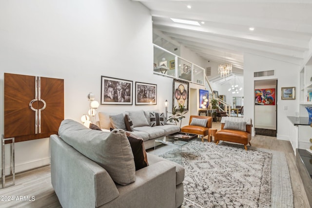 living room with light hardwood / wood-style flooring, lofted ceiling with beams, and an inviting chandelier