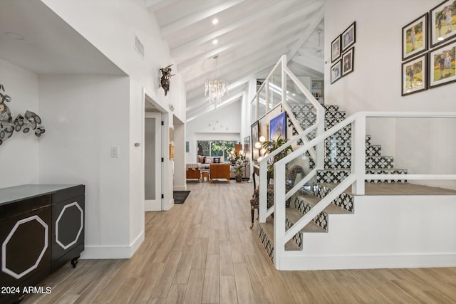 stairway featuring a notable chandelier, hardwood / wood-style floors, and high vaulted ceiling