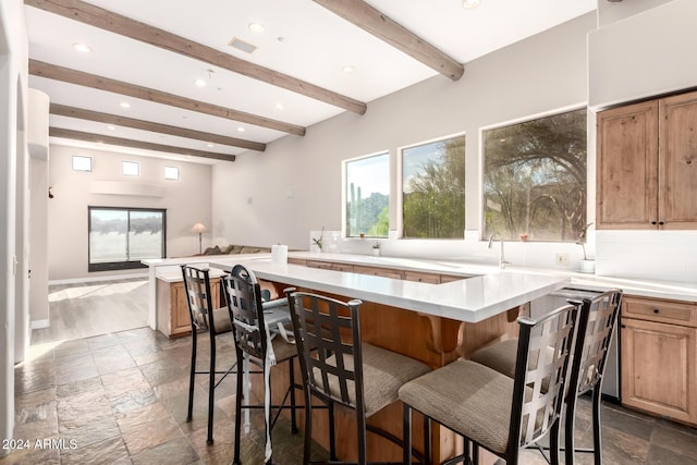 kitchen with a kitchen breakfast bar, tasteful backsplash, a kitchen island, and beam ceiling