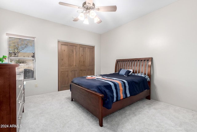 bedroom with a closet, light colored carpet, and ceiling fan