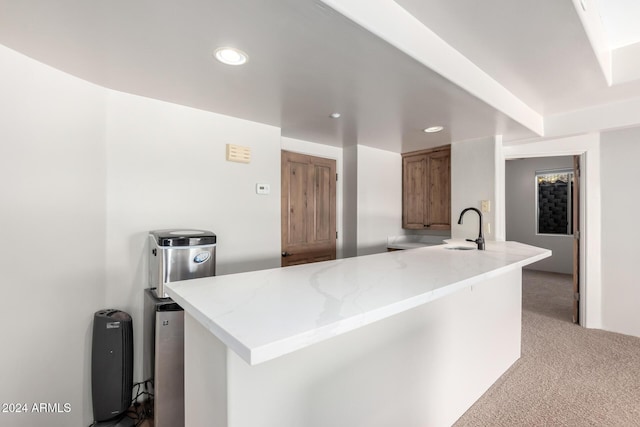 kitchen with kitchen peninsula, light carpet, and sink