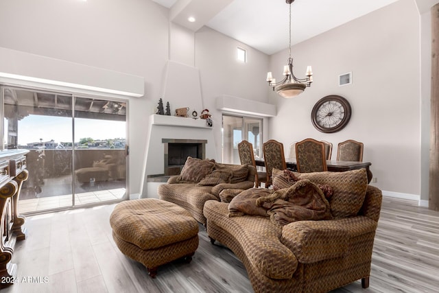 living room featuring a notable chandelier, light wood-type flooring, and a towering ceiling