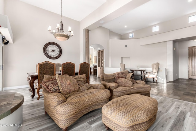 living room with a towering ceiling, hardwood / wood-style flooring, and an inviting chandelier