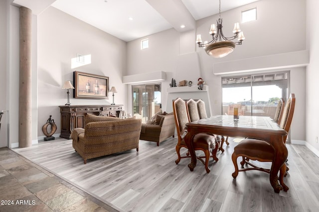 dining area with light wood-type flooring, a towering ceiling, and an inviting chandelier