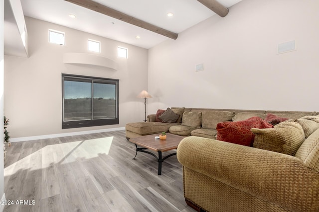 living room with a towering ceiling, light hardwood / wood-style flooring, and beamed ceiling