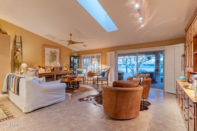 living room with light tile patterned floors, lofted ceiling with skylight, and ceiling fan