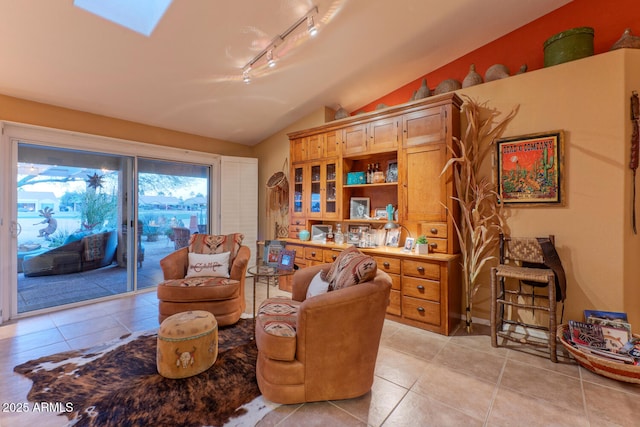 living area featuring light tile patterned floors, rail lighting, and lofted ceiling