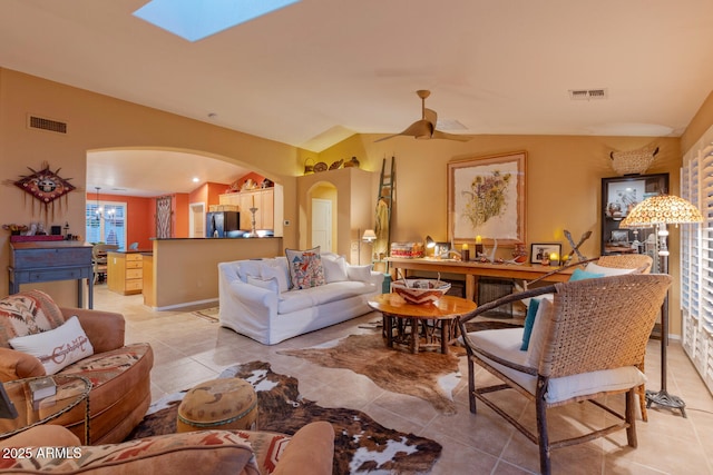 tiled living room featuring ceiling fan and lofted ceiling with skylight