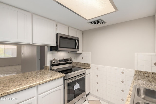 6818 N 35th Ave Unit C, Phoenix, AZ 85017 - kitchen with stainless steel appliances, tile walls, white cabinetry, and wainscoting