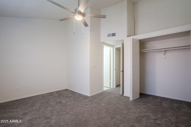 unfurnished bedroom with ceiling fan, dark carpet, and a closet