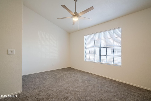 spare room with ceiling fan, dark carpet, and lofted ceiling