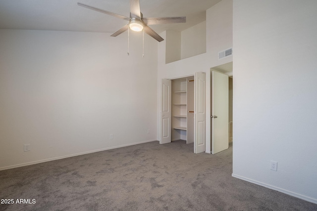 unfurnished bedroom featuring ceiling fan, a closet, light colored carpet, and a towering ceiling