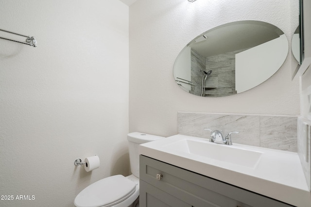 bathroom with toilet, vanity, and tasteful backsplash