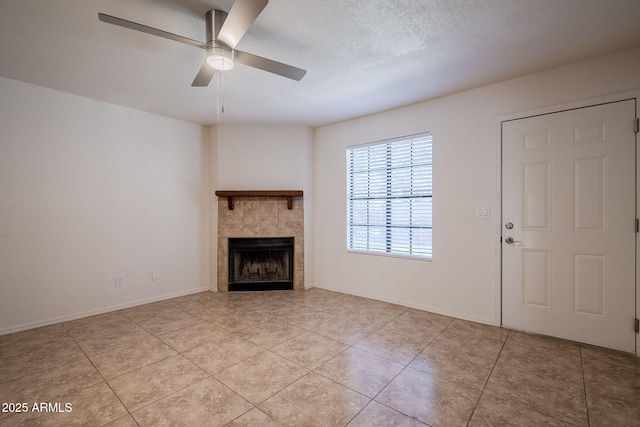 unfurnished living room featuring ceiling fan, light tile patterned floors, a tile fireplace, and a textured ceiling